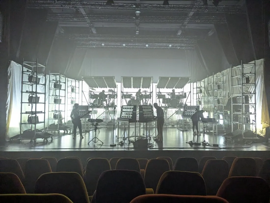 Soulwax's three-drummer set backlit white during soundcheck in a theatre